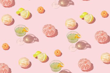 Creative pattern made of exotic cocktail in crystal glass and citrus fruits on pink background. Minimal summer concept.