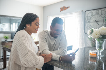 Smiling couple looking at smart phone in kitchen