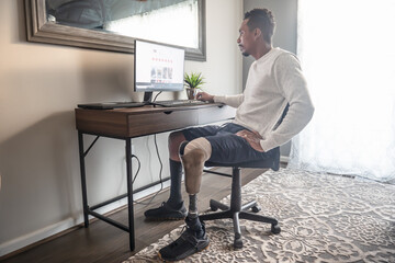 Man with prosthetic leg using computer at home