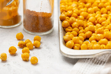 Indian traditional crispy, salty, savory snack - roasted chickpeas covered with spices curry powder, garam masala and turmeric on a baking sheet. Selective focus, low depth of field