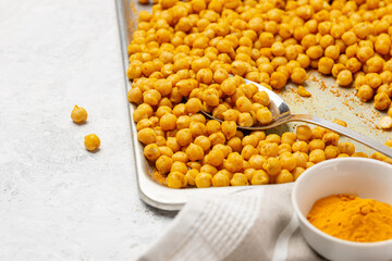 Indian traditional crispy, salty, savory snack - roasted chickpeas covered with spices curry powder, garam masala and turmeric on a baking sheet. Selective focus, low depth of field