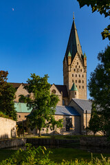 Fototapeta na wymiar Paderborn Cathedral in Westphalia Germany with impressive big bell tower on a blue sky summer day. Catholic church monument and tourist pilgrim attraction, near Pader sources in historic town centre.