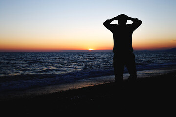Fototapeta premium the silhouette of a man who saw the sea and clutched his head for joy, the joy of vacation