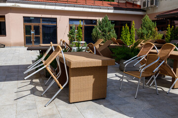 the summer street cafe is empty, the chairs are leaning against the tables