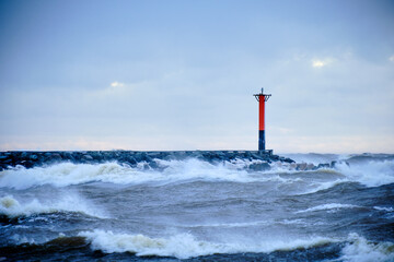 lighthouse on a windy storm on a baltic sea at winter with clouds in the sky - obrazy, fototapety, plakaty