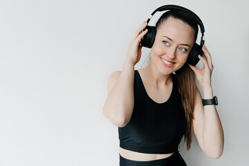 Young pretty woman wearing headphones listening to music and smiling over white background at studio. Music lover concept