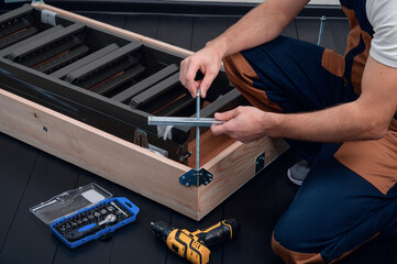 A uniformed worker attaches a level adjustment guide to the door frame of the attic staircase.