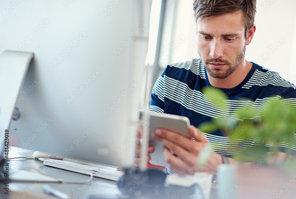 Poster tools of the designing trade. shot of a casually-dressed young man using a digital tablet at his des