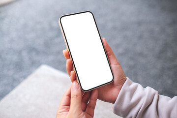 Mockup image of a woman holding and using mobile phone in the outdoors