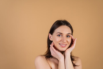 Close-up beauty portrait of a topless woman with perfect skin and natural make-up, with anti-aging cream dots to moisturize and firm the skin under the eyes.