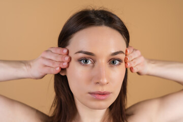 Obraz premium Close beauty portrait of a topless woman with perfect skin and natural makeup, shiny lips, on a beige background