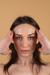 Fototapeta premium Close beauty portrait of a topless woman with perfect skin and natural makeup, shiny lips, on a beige background