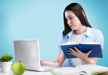 Exhausted lady sitting at the table, writing in a notebook, studying