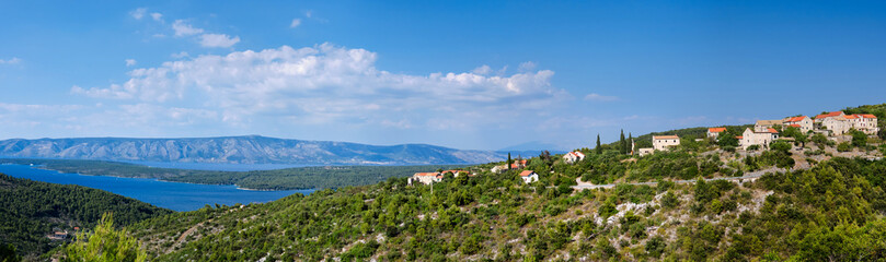 Fototapeta premium Panoramic banner image of Hvar island in Croatia. Aerial view on mountains and coastline with blue water. Bird view panoramic image taken from old mountain road to Hvar.