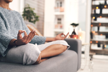 I could sit here all day. Cropped shot of an unrecognizable woman sitting in a lotus position alone and meditating in her living room at home.