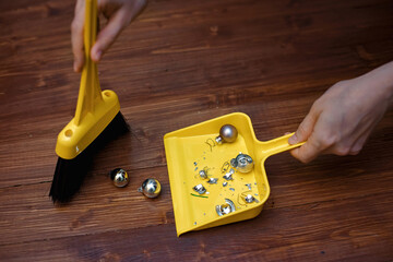 Female hand removing damaged glass balls from wooden floor, broken Christmas bauble, clean up after...