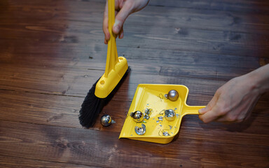 Female hand removing damaged glass balls from wooden floor, broken Christmas bauble, clean up after...