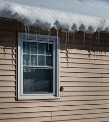 Snow and ice cycles hang over the eave of this house in Upstate NY as it begins to melt and slide off the roof.