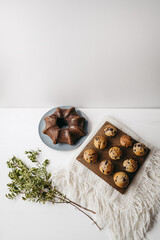 Homemade muffins with blueberries on brown wooden board on white table, boho napkin, leaves. Tasty cakes, sweets, cupcakes. No sugar, free gluten. Receipt of keks. Sweet dessert buffet. Holiday.
