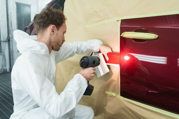 Colorist man compare color sample with car paint using special lamp