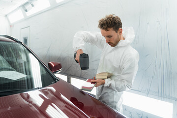 Car painter man determines the correct tone of a vehicle body colour using a special colorist's...