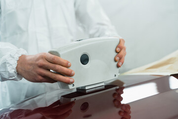 Close-up view of a auto painter determining the exact shade of a car's color using an electronic scanner