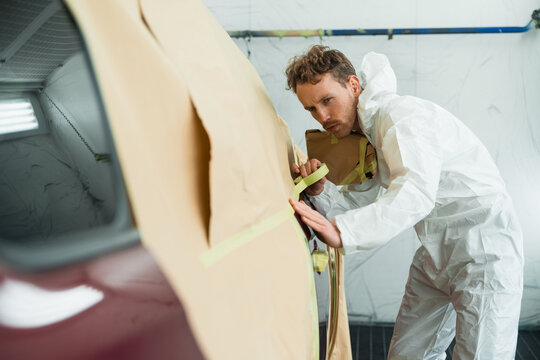 Man masking a car body before painting