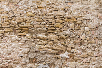 A very old and often patched wall from irregular shaped and variable sized  stones and bricks