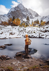 Hiker enjoying view at Orlenok Lake during autumn in North Caucasus, Arkhyz, Karachay-Cherkessia, Russia. concept of travel and active lifestyle