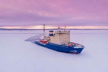Fototapeta premium Icebreaking vessel in Arctic with background of sunset