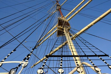 Obraz premium A close-up of the masts and ropes of a sailing ship. Blue sky background.