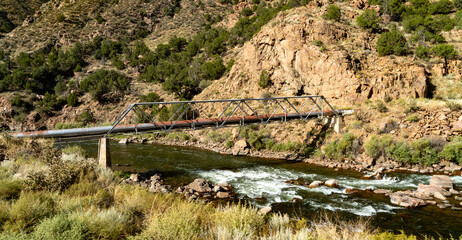 A pipeline and pipeline bridge crossing the Animas River in the San Juan mountains gorge on the...