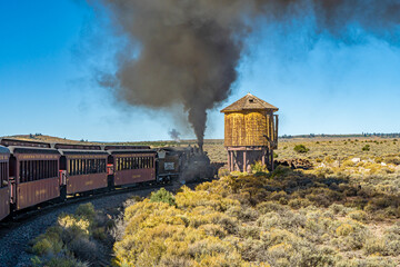 Fototapeta na wymiar Antonio, Colorado - 9-21-2021: A steam engine locomotive and passenger cars on the Cumbris & Toltec scenic railroad near Antonio colorado, also water tower,