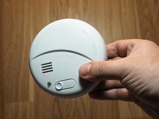 Photoelectric smoke detector. Hand with smoke detector. Residential fire safety devices - obrazy, fototapety, plakaty