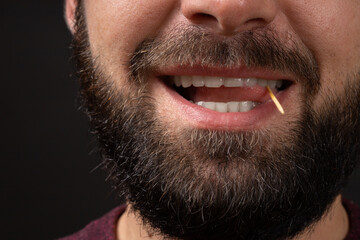 smiling male unshaven face close-up with open mouth and tongue playing with toothpick, bad man manners and violation of etiquette. - obrazy, fototapety, plakaty