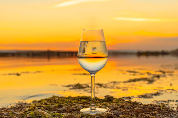 Verre à pied sur un étang au coucher de soleil.