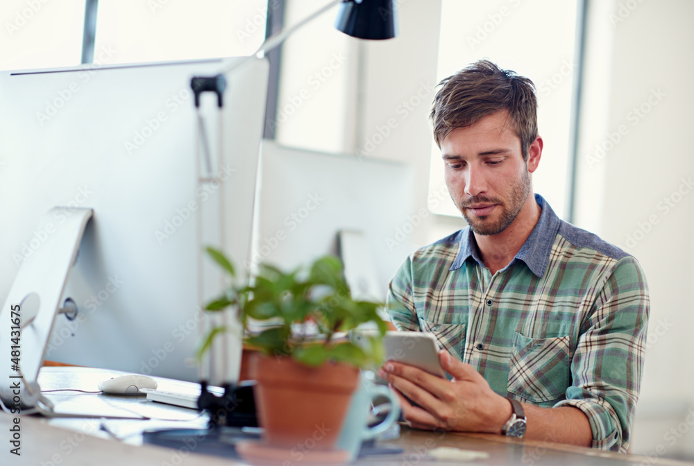 Poster wirelessly syncing his devices. shot of a casually-dressed young man using a digital tablet at his d