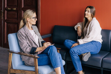 The conversation of a female psychotherapist with a woman in the office during the session. The psychologist makes a social survey of the reference group. A professional is talking to a client. - obrazy, fototapety, plakaty