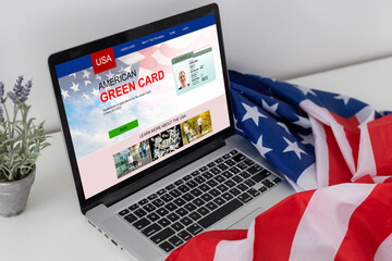 Green card in a search engine on the computer. laptop and american flag