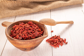 Dried goji berries in a wooden cup and with a wooden spoon on a wooden table, macro.