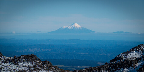 Snow covered Mount Taranaki, or Egmont, an active volcano, viewed from far away in tongariro national park, New Zealand.