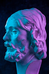 Colorful gypsum copy of ancient statue of John the Baptist head for artists on a dark textured background. Plaster sculpture man face. John baptized Jesus. Art poster in purple and blue bright colors.