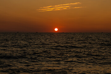Beautiful orange sunrise is on the beach by the sea with black ship silhouettes