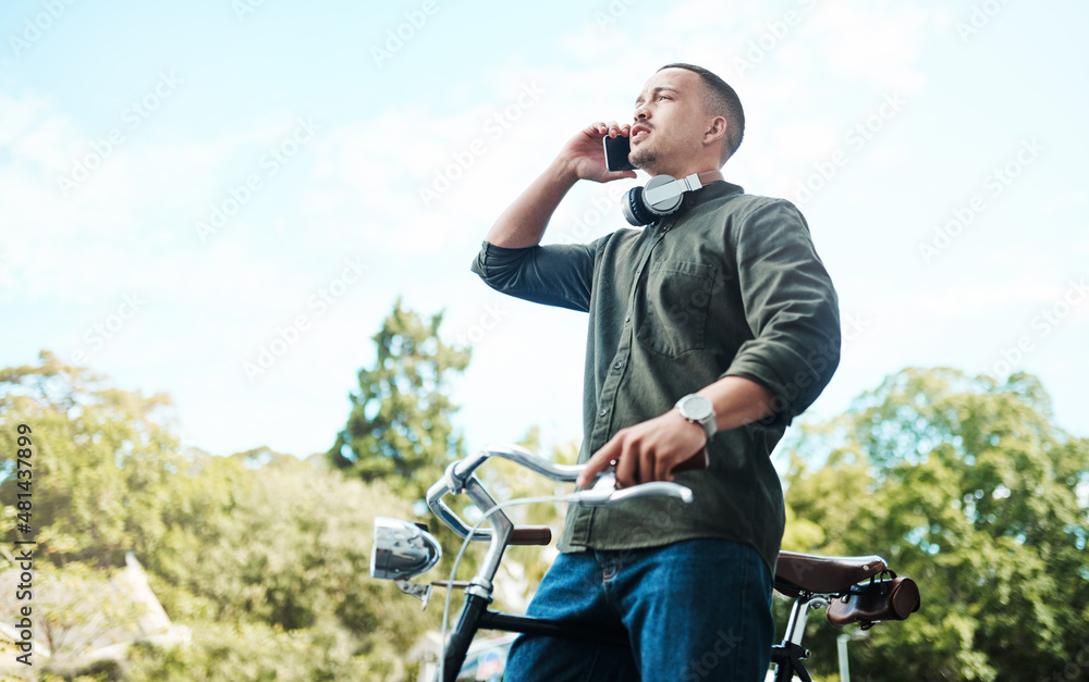 Poster there's power in perseverance. shot of a young businessman using a smartphone while riding his bicyc