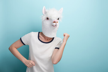 Young woman in alpaca mask perform cheerful carefree dance moves, isolated on blue background.