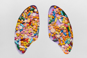 Cut paper with shape of human lungs and pills on color background