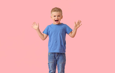 Emotional little boy in blue t-shirt on pink background
