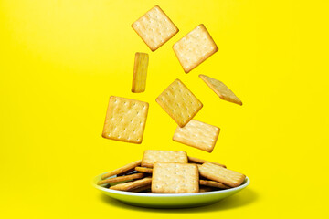 Crackers on a yellow background. Crackers fall into the plate. fresh biscuits