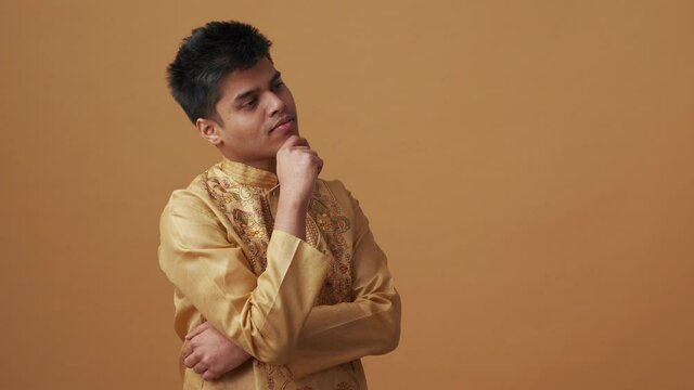 Pensive Indian man in national cloth having idea in the orange studio