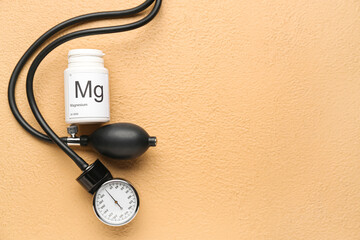 Bottle of magnesium pills and sphygmomanometer on color background